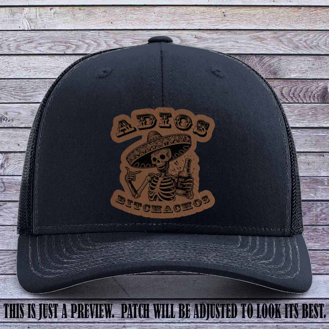 Dark brown leather patch on Navy Richardson 112 trucker hat featuring “Adios Bitchachos” skeleton design.