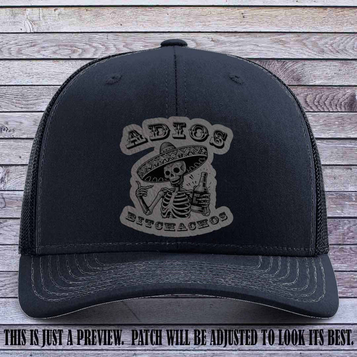 Grey leather patch on Navy Richardson 112 trucker hat featuring “Adios Bitchachos” skeleton design.