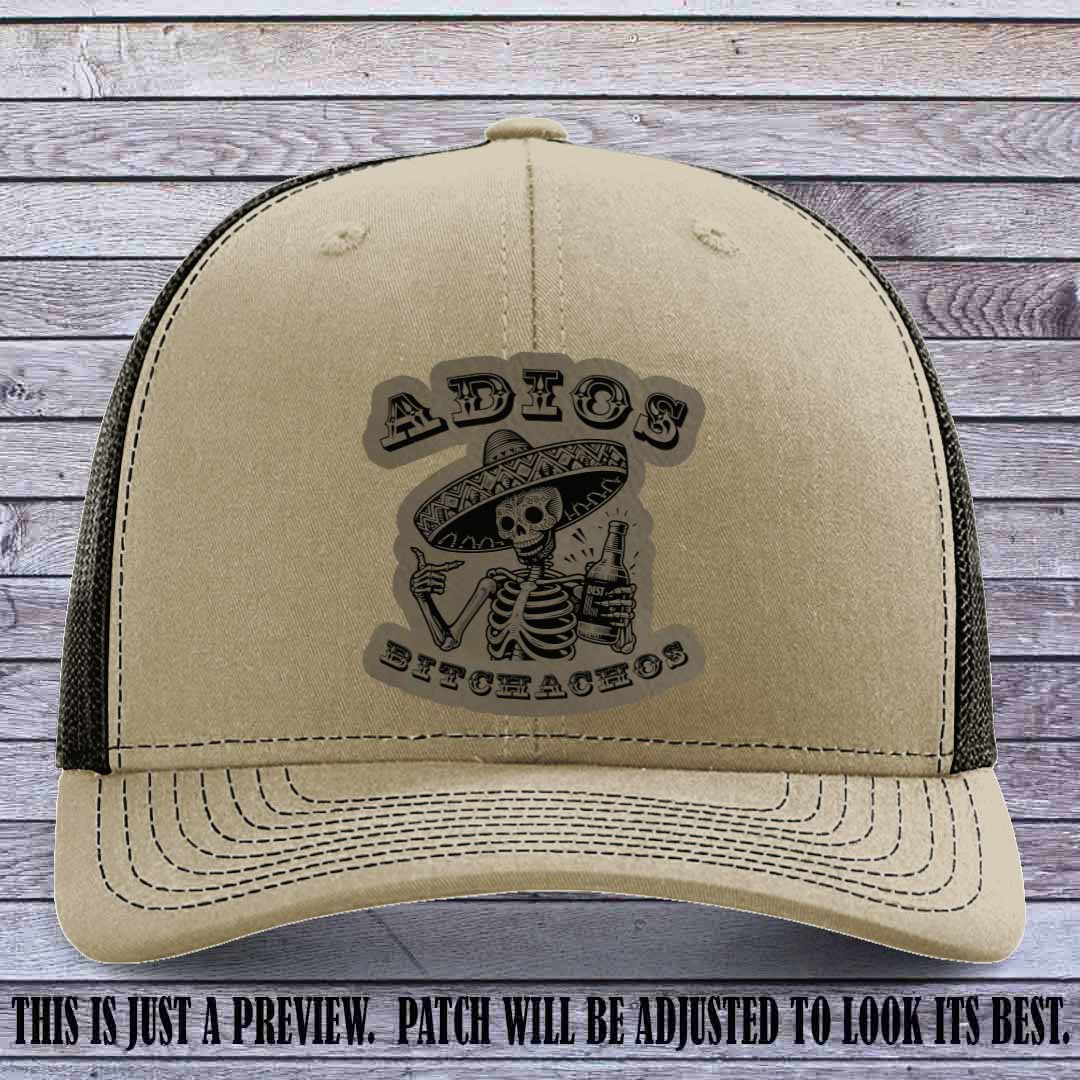 Light brown leather patch on Khaki to Coffee Richardson 112 trucker hat featuring “Adios Bitchachos” skeleton design.