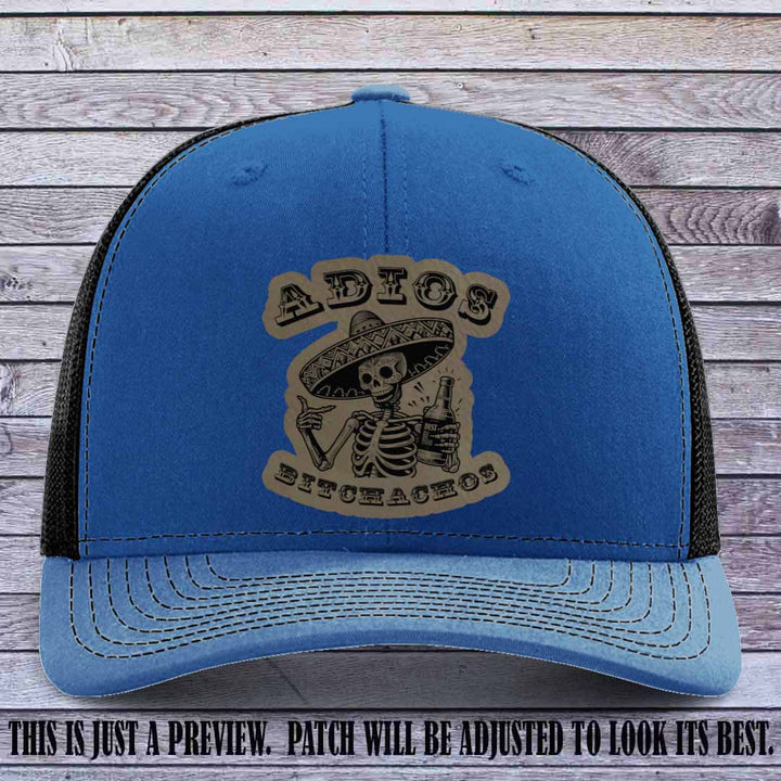 Light brown leather patch on Royal to Black Richardson 112 trucker hat featuring “Adios Bitchachos” skeleton design.