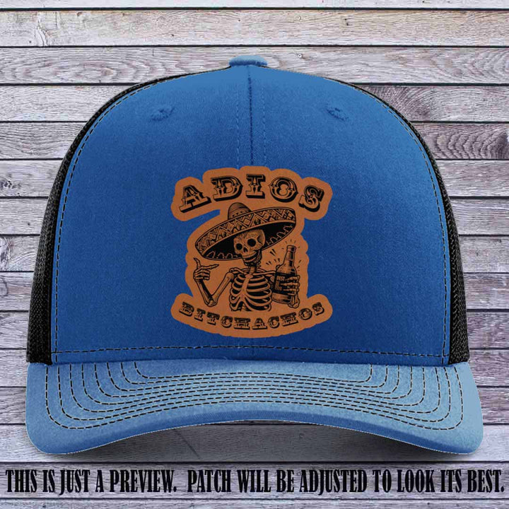Rawhide leather patch on Royal to Black Richardson 112 trucker hat featuring “Adios Bitchachos” skeleton design.