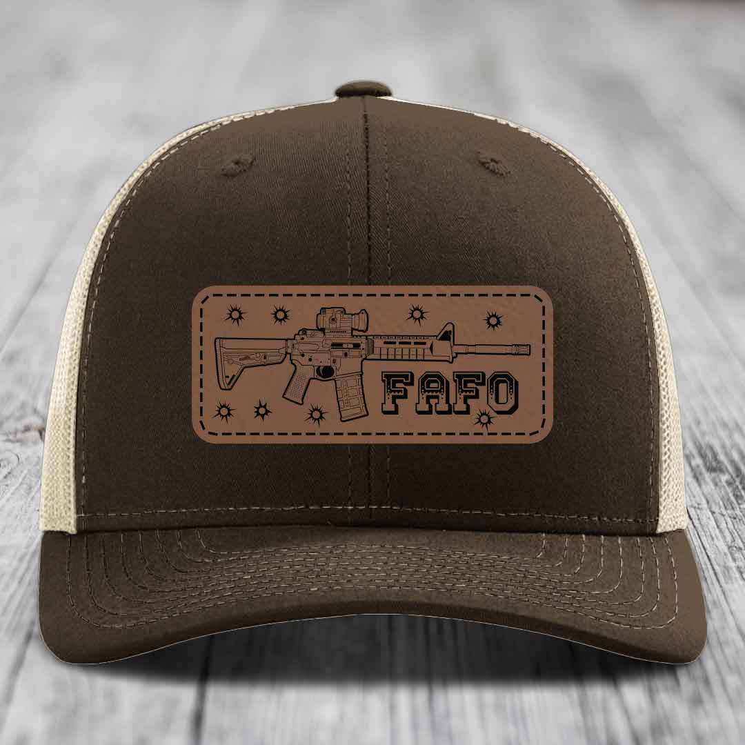 Brown trucker hat with beige mesh back and a tan leather patch featuring an AR-15 rifle outline and &