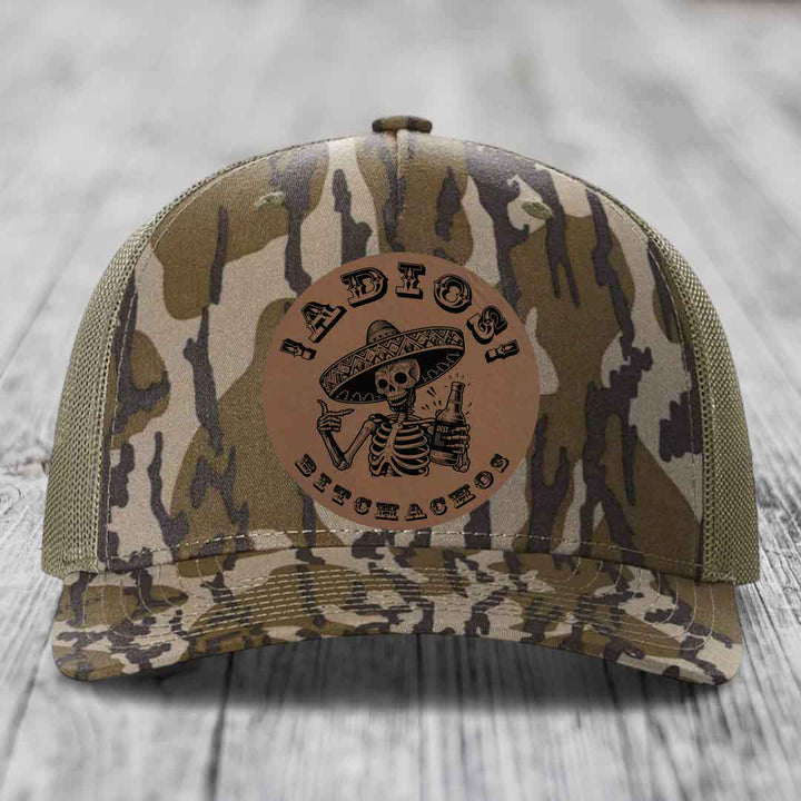 Camouflage trucker hat with brown leather patch featuring skeleton in sombrero holding beer bottle and text &