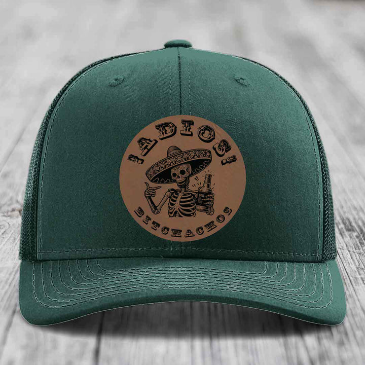 Green trucker hat with brown circular patch featuring skeleton in sombrero holding beer bottle and text &