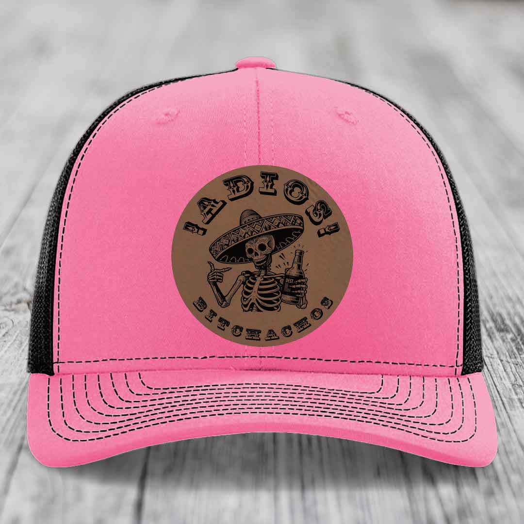 Pink trucker hat with black mesh back and a brown leather patch featuring a skeleton in a sombrero holding a beer bottle with text &