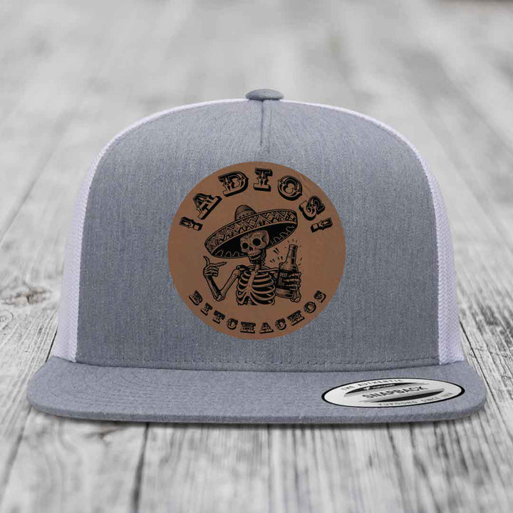 Grey trucker hat with brown leather patch featuring skeleton in sombrero holding beer bottle.