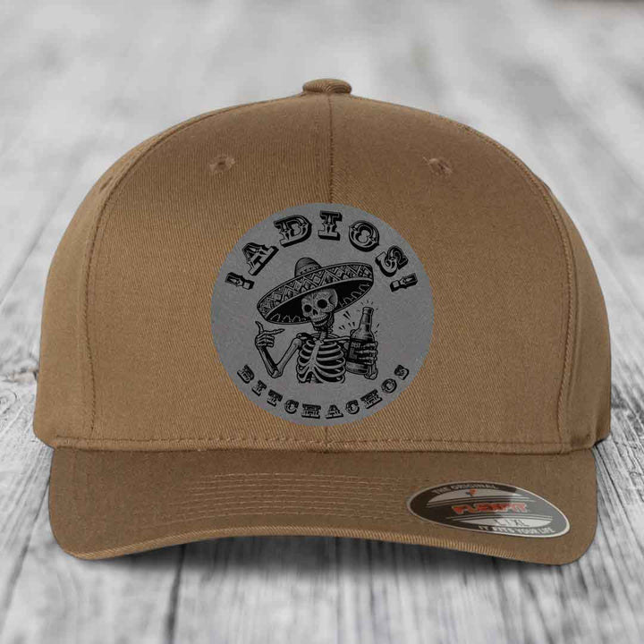 Tan baseball cap with grey circular patch featuring skeleton in sombrero holding beer and text &