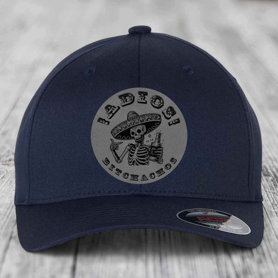 Dark blue baseball cap with circular grey patch featuring a skeleton in a sombrero holding a beer bottle and the text &