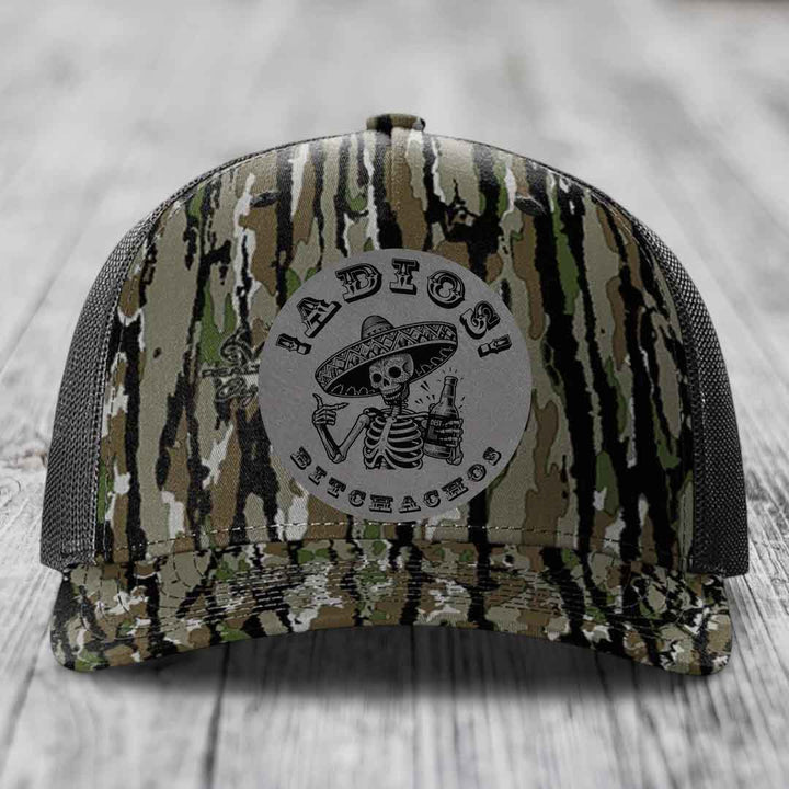 Camouflage trucker hat with grey circular patch featuring skeleton in sombrero holding beer bottle and text &