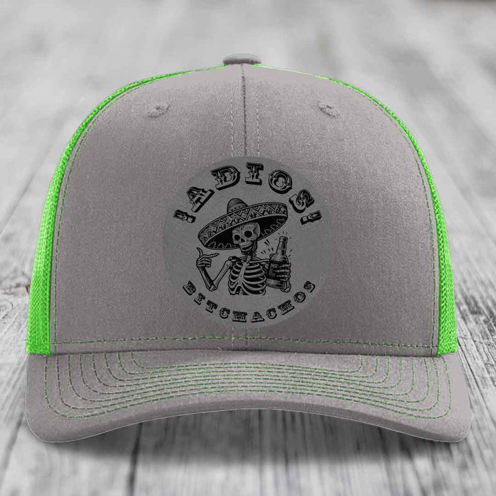 Grey trucker hat with neon green mesh and stitching, featuring a black skeleton in a sombrero holding a beer bottle with &
