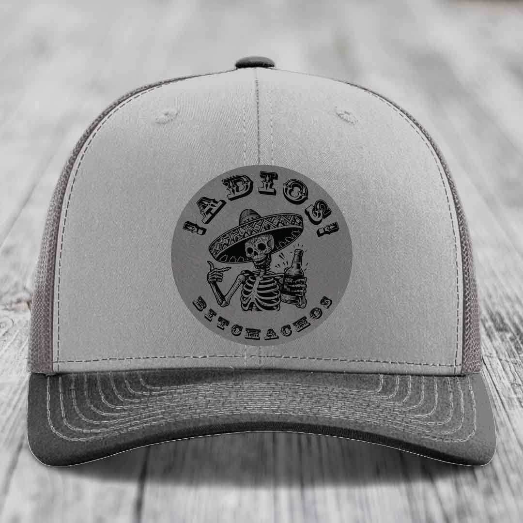 Grey trucker hat with black embroidered skeleton wearing sombrero holding beer bottle and text &