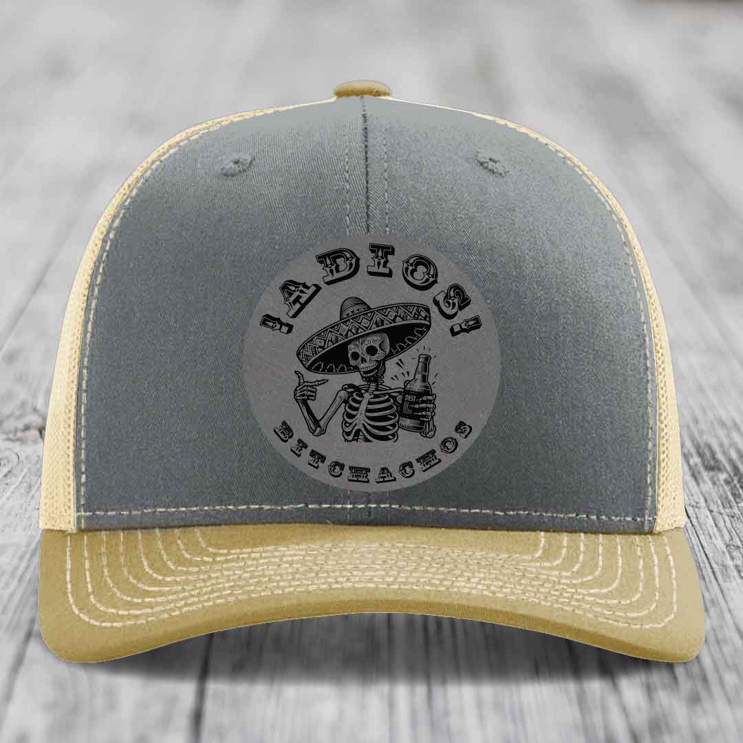 Grey and beige trucker hat with skull wearing sombrero holding beer bottle, text &