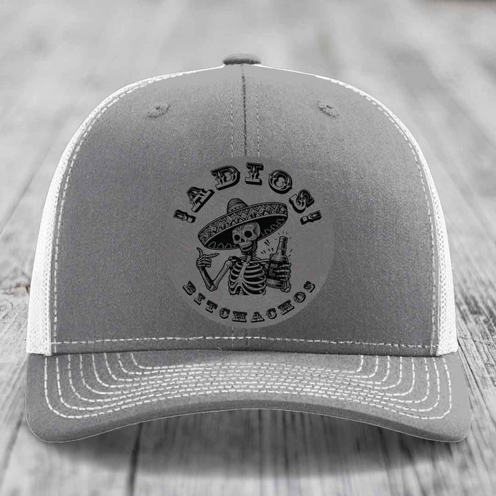 Grey trucker hat with white mesh back and embroidered skull holding beer bottle design.