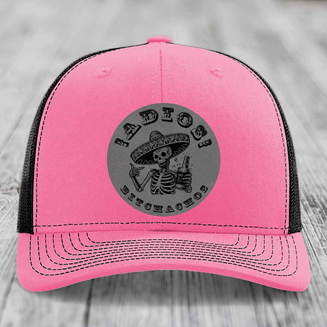 Pink trucker hat with black mesh back and gray circular patch featuring a skeleton in a sombrero holding a beer bottle with text &