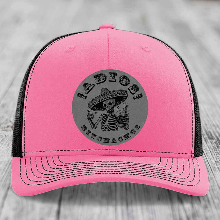 Pink trucker hat with black mesh back and gray circular patch featuring a skeleton in a sombrero holding a beer bottle with text &