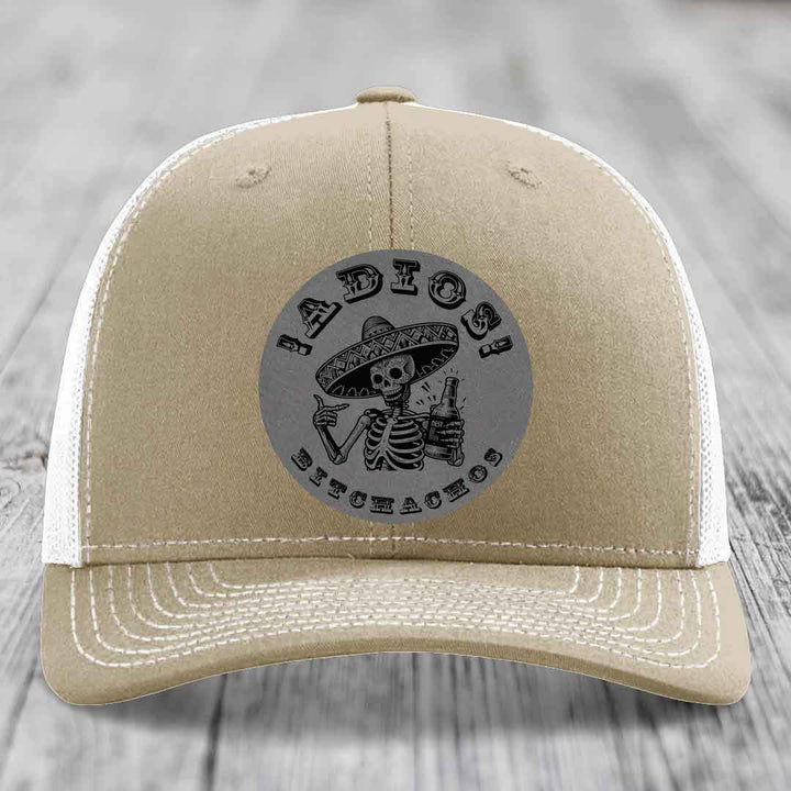 Tan trucker hat with white mesh back and embroidered skull patch reading &