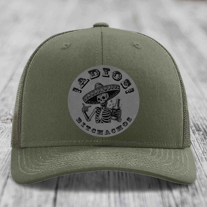 Olive green trucker hat with a circular patch featuring a skeleton in a sombrero holding a beer bottle and the text &