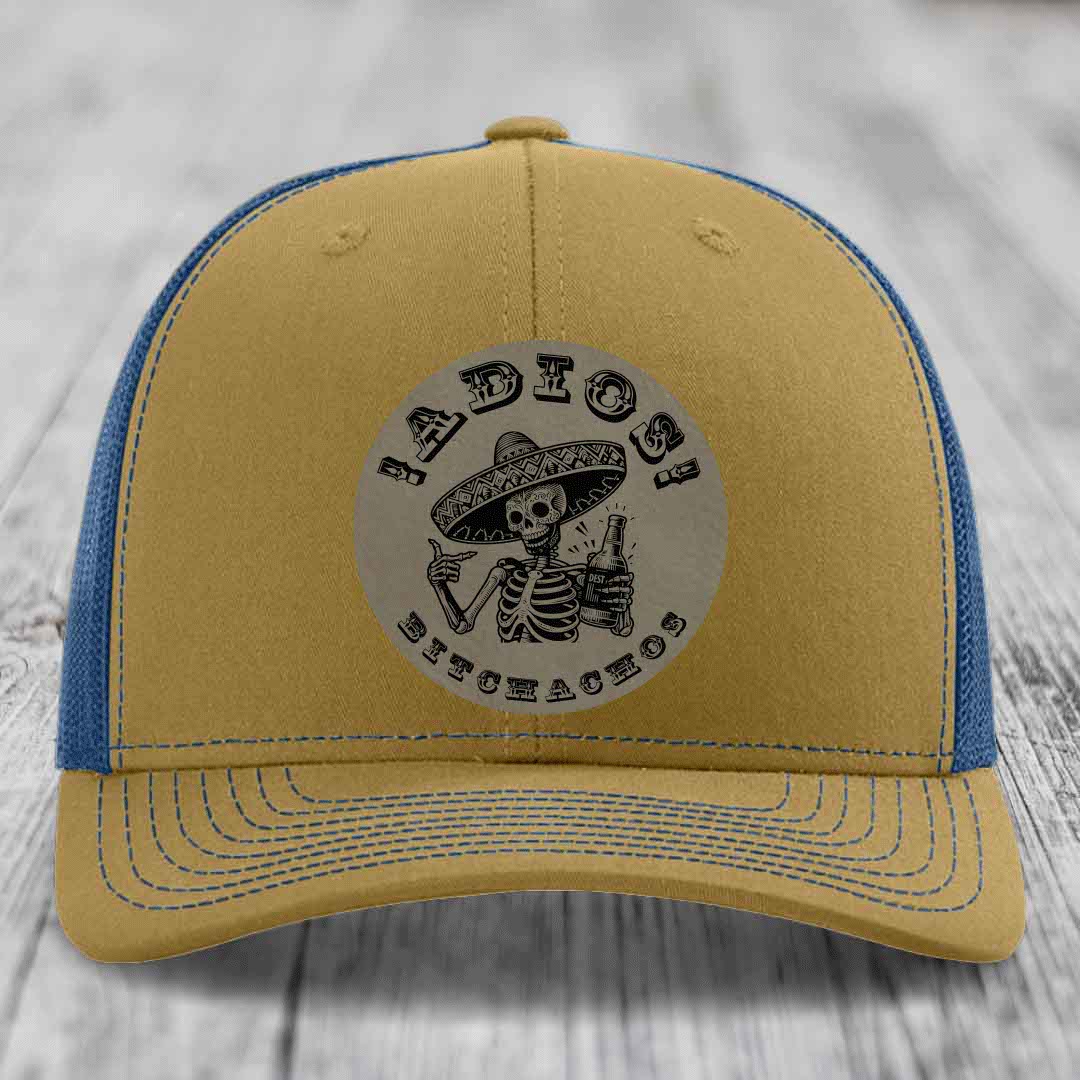 Tan and blue trucker hat with skull graphic patch reading &