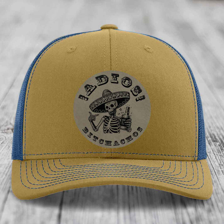 Tan and blue trucker hat with skull graphic patch reading &