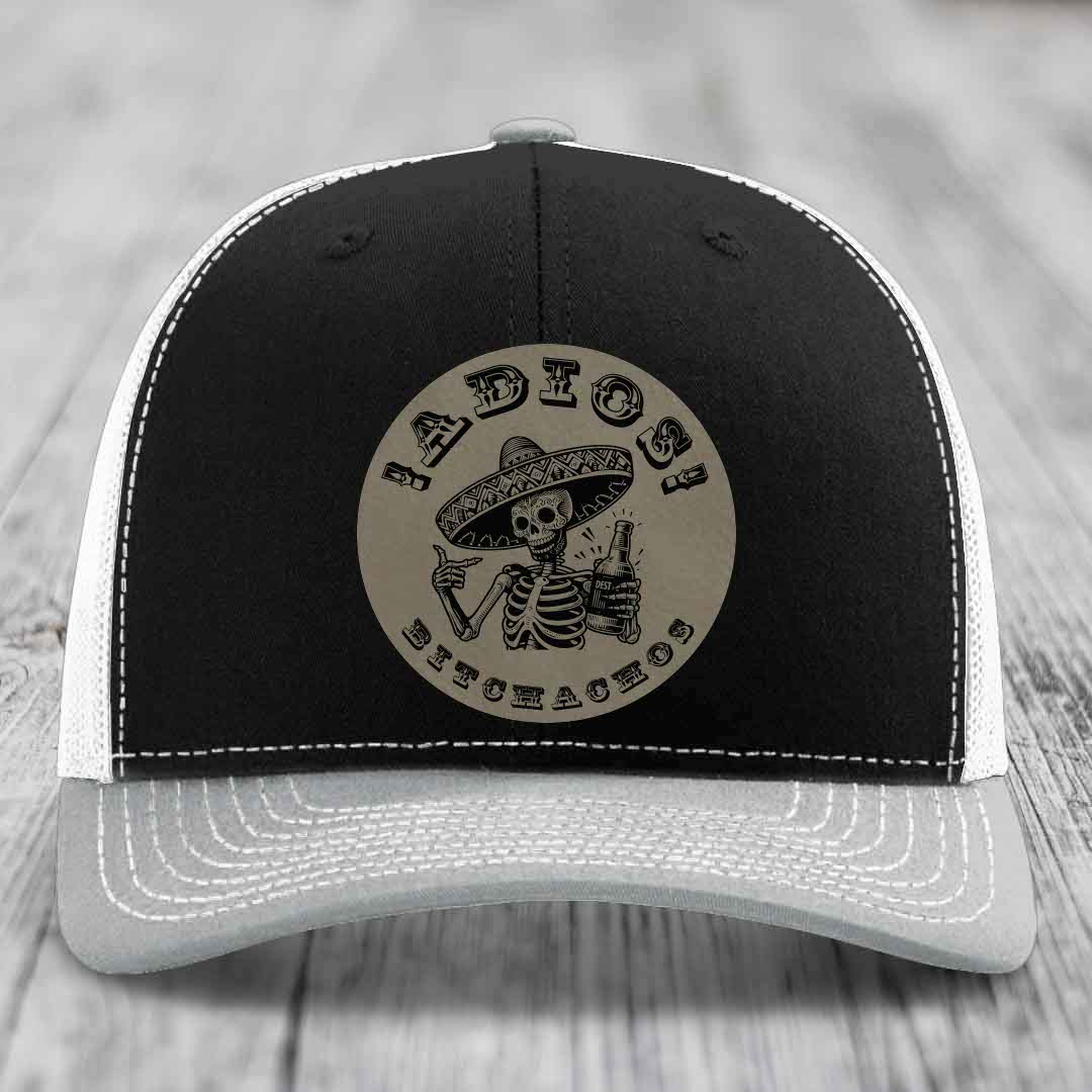 Black and white trucker hat with a circular leather patch featuring a skeleton in a sombrero holding a beer bottle.
