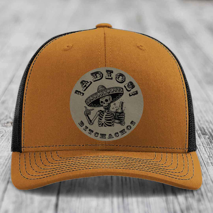 Orange and black trucker hat with a circular patch featuring a skeleton in a sombrero holding a beer bottle.