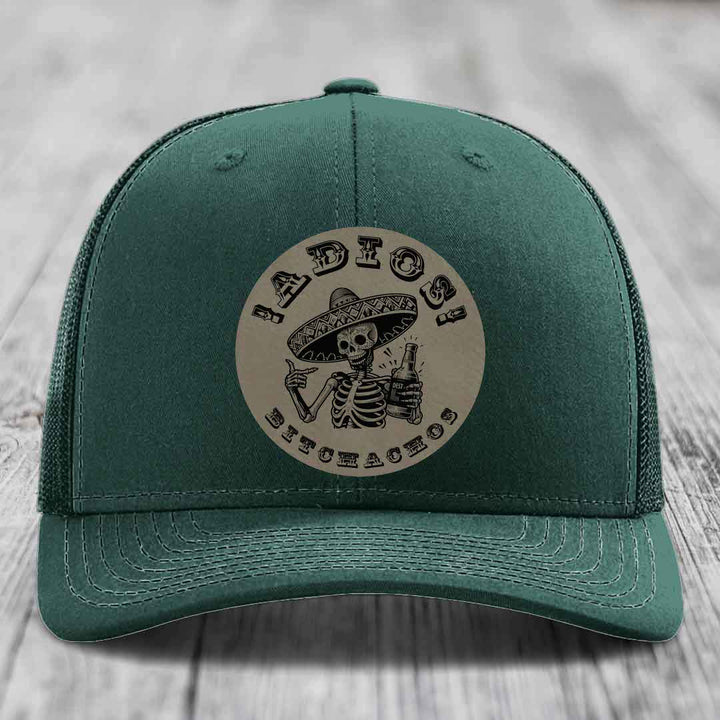 Green trucker hat with a circular patch featuring a skeleton in a sombrero holding a beer bottle and the text &