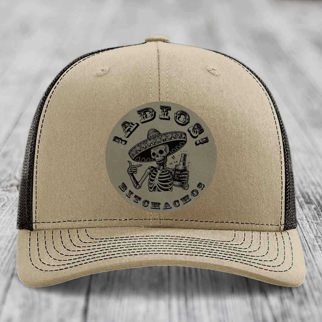 Beige trucker hat with black mesh back and embroidered skull graphic holding a beer bottle.