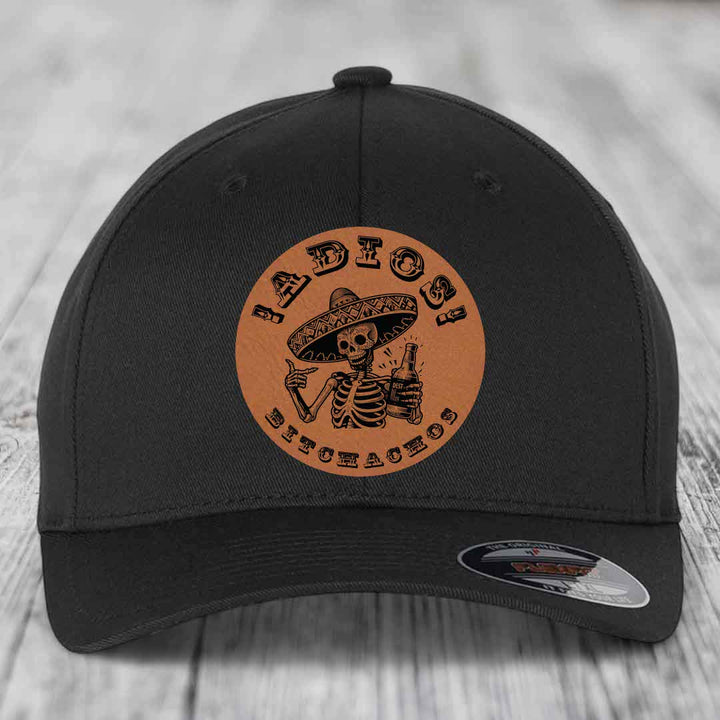 Black baseball cap with brown leather patch featuring skeleton in sombrero holding beer and text &