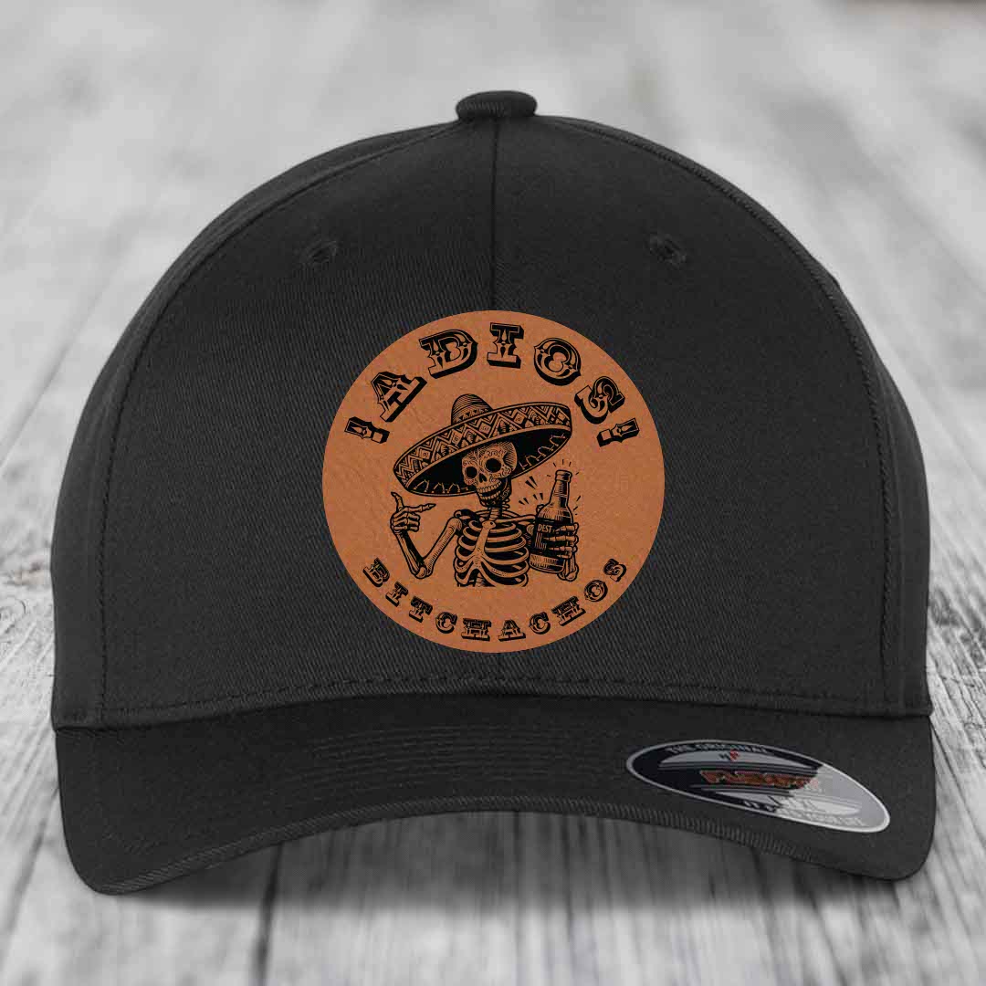 Black baseball cap with brown leather patch featuring skeleton in sombrero holding beer bottle and text &