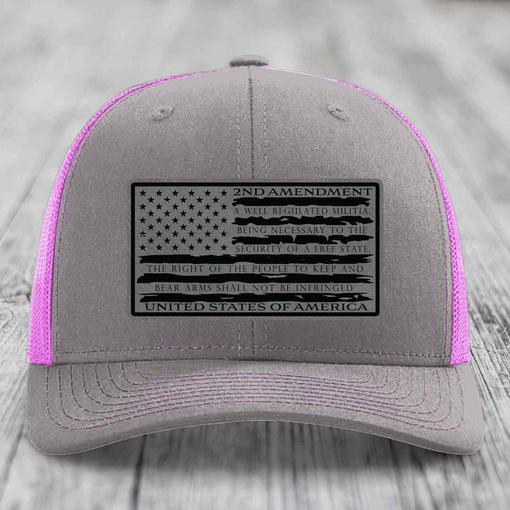 Grey trucker hat with pink mesh sides and a black 2nd Amendment patch featuring the American flag design.