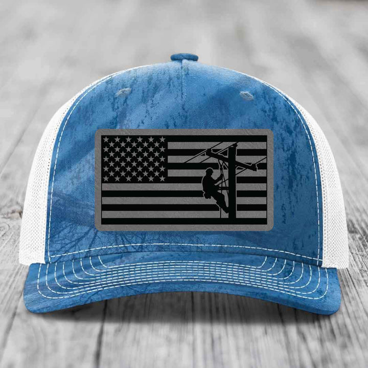 Blue and white trucker hat with American flag patch featuring lineman silhouette.