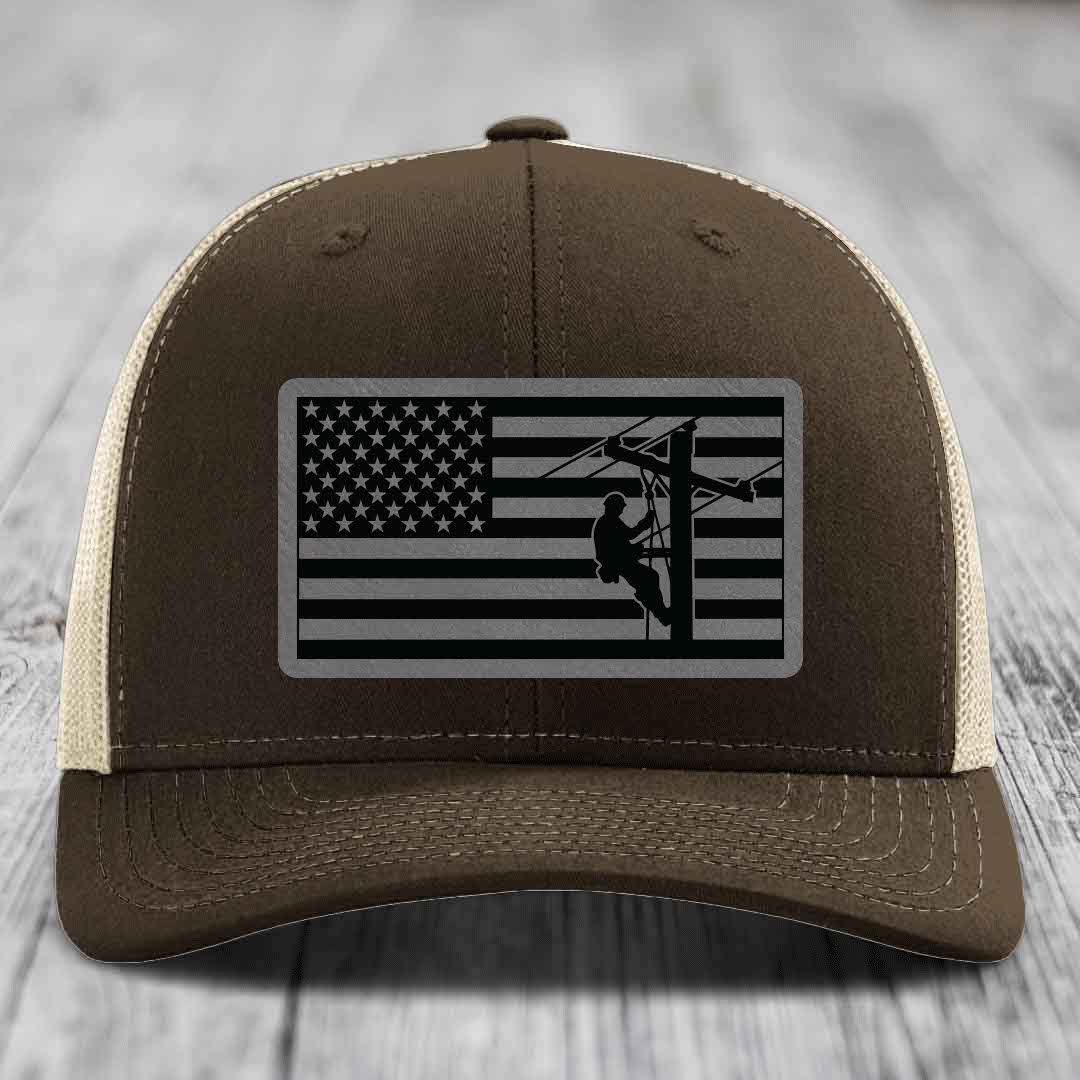 Brown trucker hat with American flag patch showing lineman on power pole.
