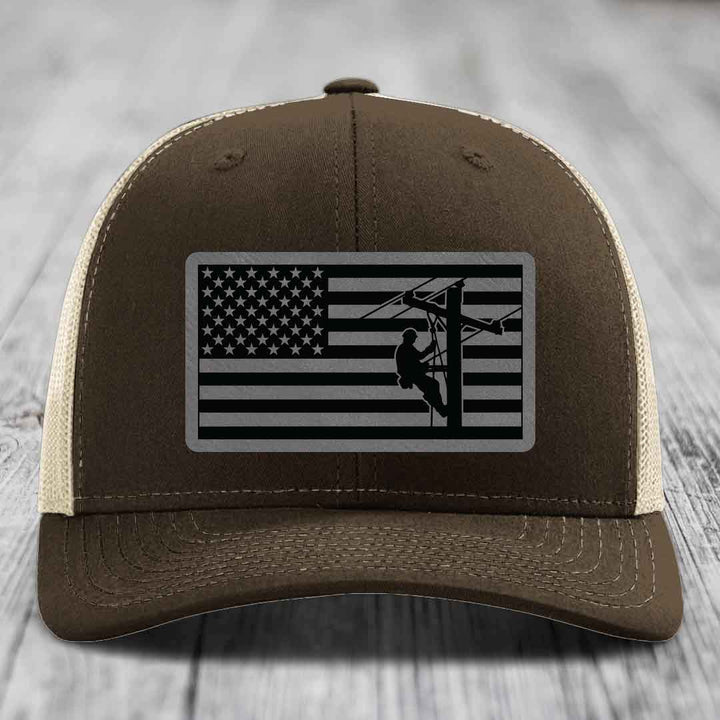 Brown trucker hat with American flag patch showing lineman on power pole.