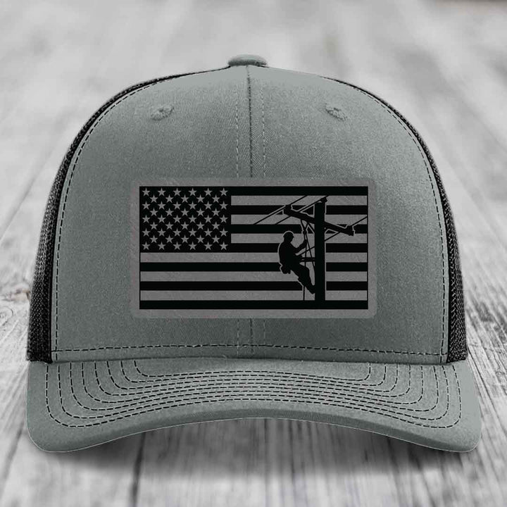 Grey trucker hat with black American flag patch featuring lineman silhouette.