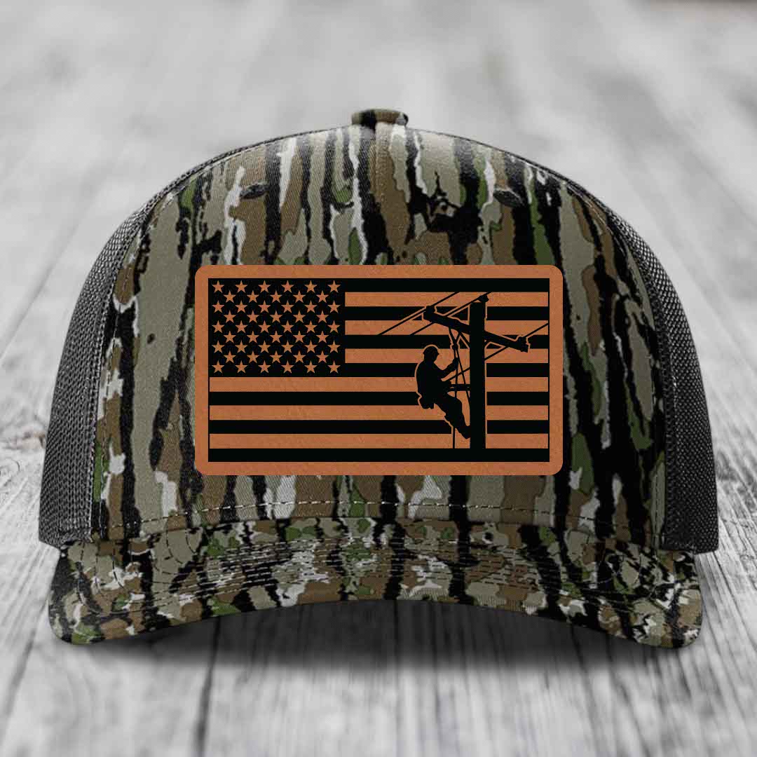 Camouflage trucker hat with American flag patch featuring lineman silhouette.