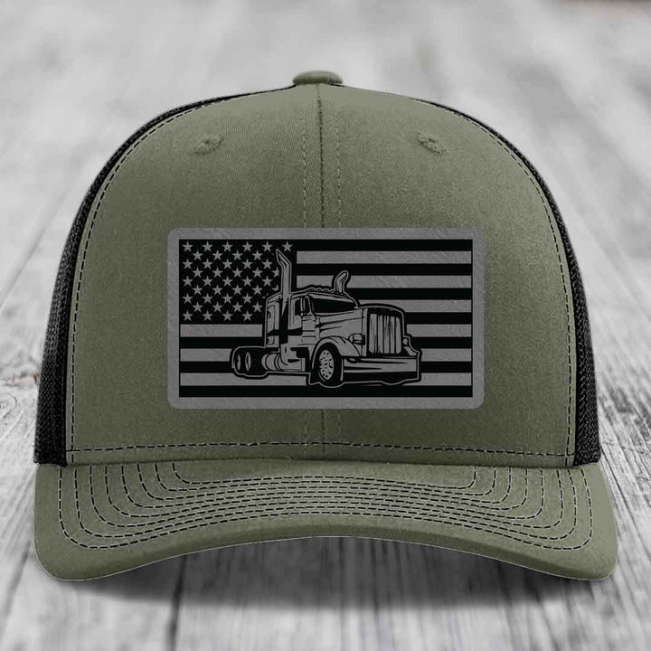 Olive green trucker hat with black mesh back, featuring a rectangular patch of an American flag with a Peterbilt truck graphic.