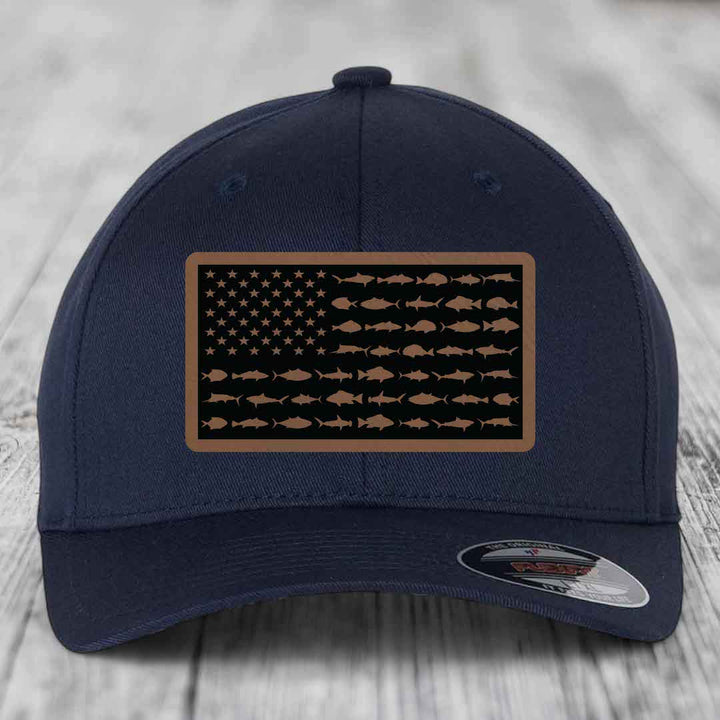 Dark blue baseball cap with a rectangular patch featuring an American flag design made of saltwater fish silhouettes.