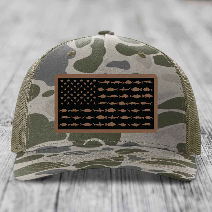 Camouflage trucker hat with American flag patch made of saltwater fish silhouettes.