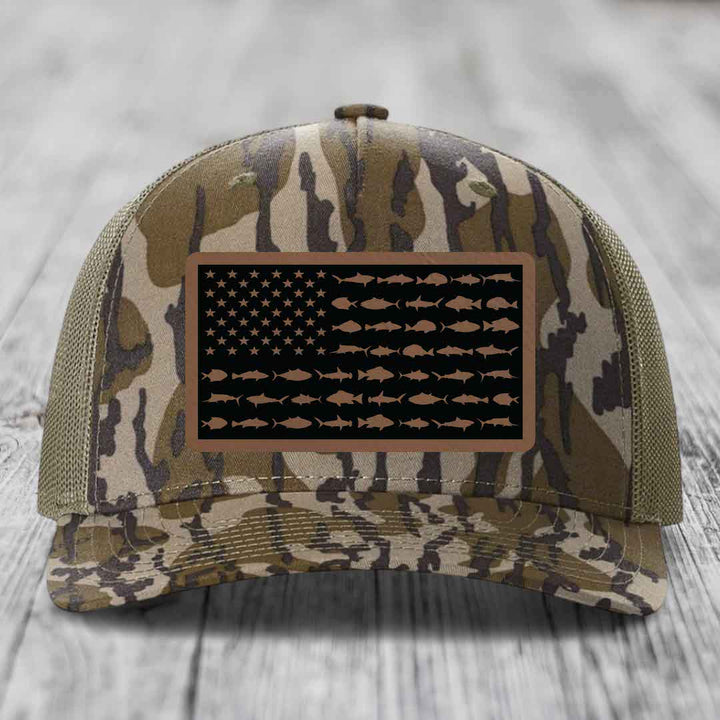 Camouflage trucker hat with American flag patch made of saltwater fish silhouettes in brown on black background.