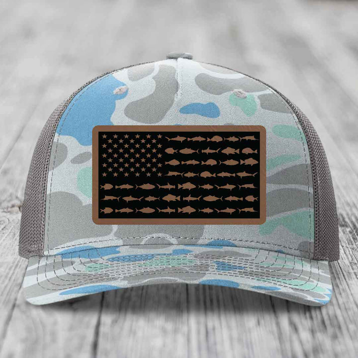 Camouflage trucker hat with American flag patch featuring fish silhouettes instead of stars and stripes.