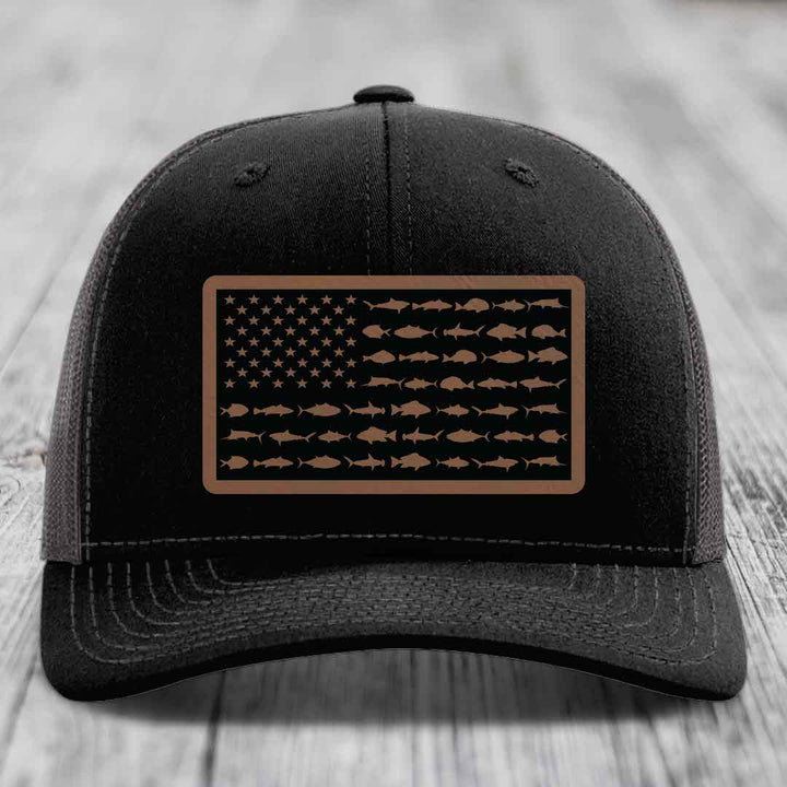 Black trucker hat with a rectangular patch featuring an American flag design made of fish silhouettes in brown.