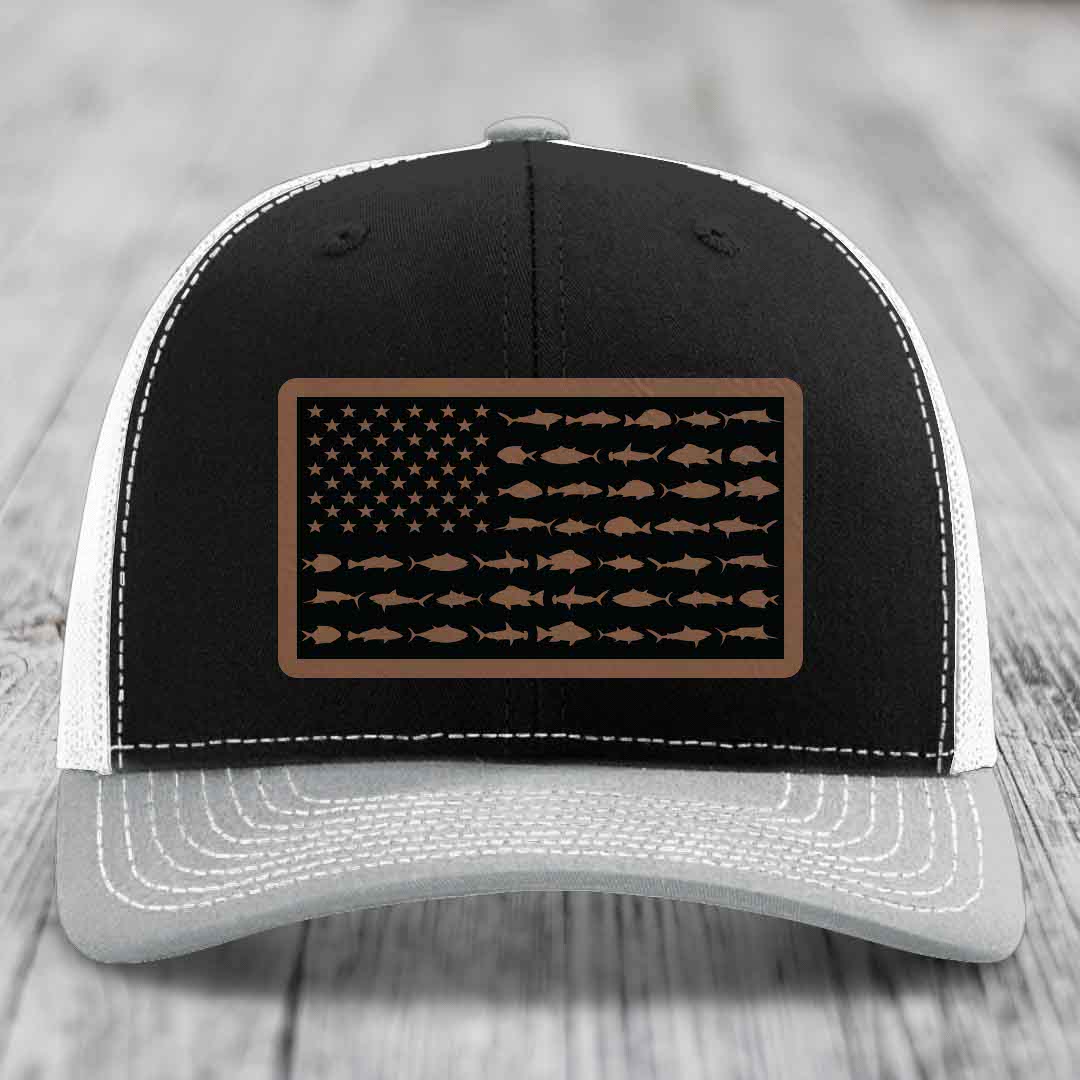Black and white trucker hat with a brown leather patch featuring an American flag design made of fish silhouettes.