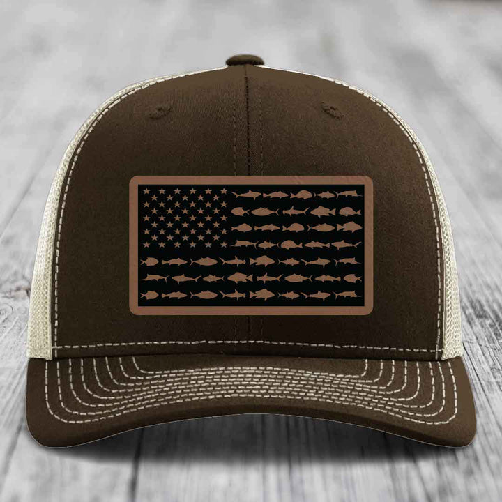 Brown trucker hat with white stitching and a rectangular patch featuring an American flag design made of fish silhouettes.