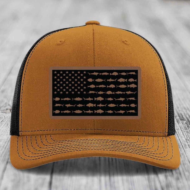 Tan trucker hat with black mesh back and a rectangular patch featuring an American flag design made of fish silhouettes.