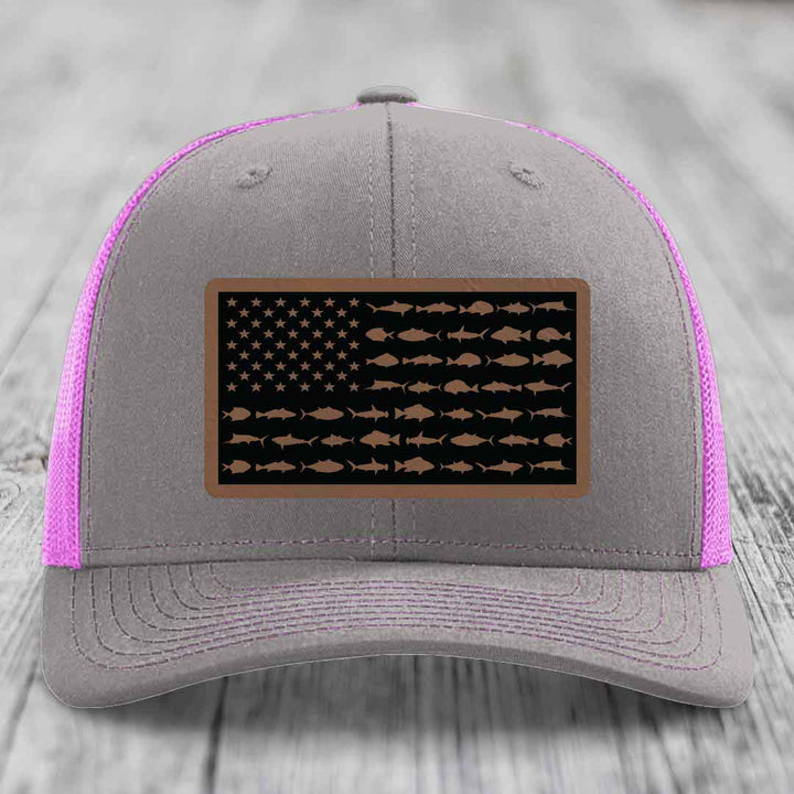 Grey trucker hat with pink mesh and a saltwater fish flag patch on front.