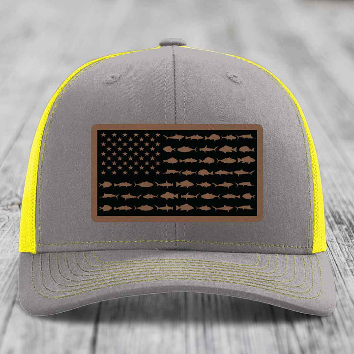 Grey trucker hat with yellow mesh and stitching, featuring a saltwater fish flag patch.