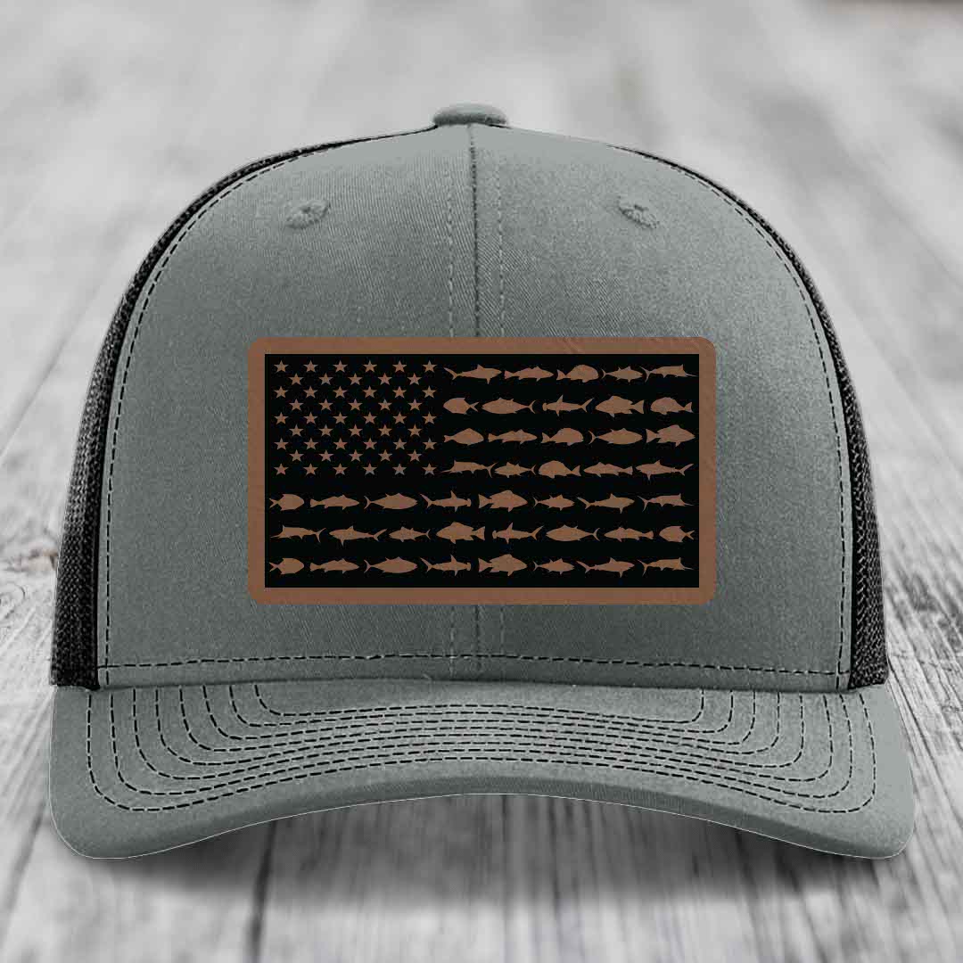 Grey trucker hat with a rectangular leather patch featuring an American flag design made of fish silhouettes.