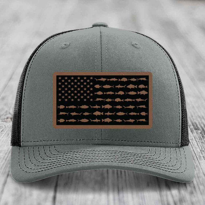 Grey trucker hat with a rectangular leather patch featuring an American flag design made of fish silhouettes.
