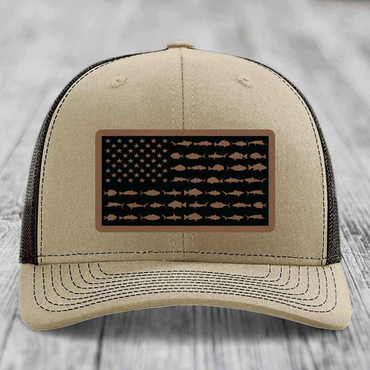 Beige trucker hat with black mesh back, featuring a rectangular patch of an American flag made of saltwater fish silhouettes.