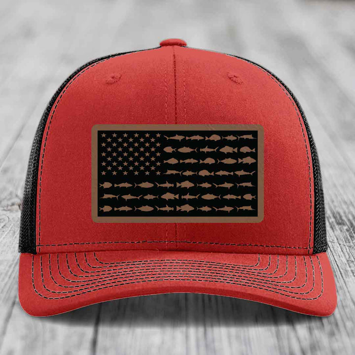 Red trucker hat with black mesh back and a rectangular patch featuring an American flag design made of fish silhouettes.